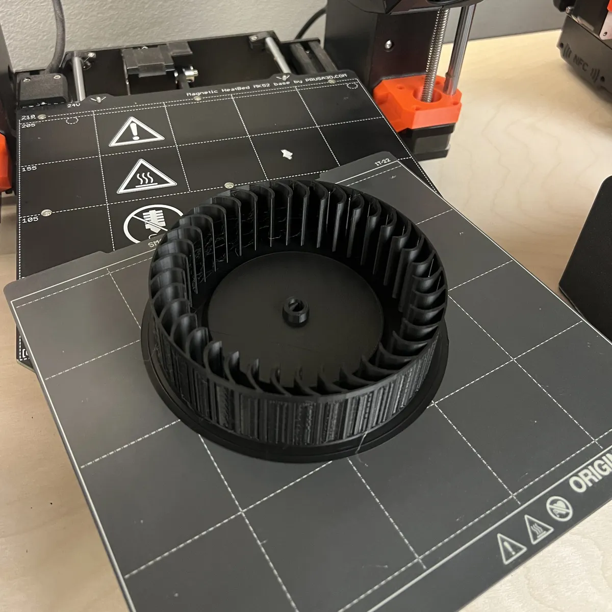 Finished black PLA replacement fan wheel on the print bed of a Prusa MK4S 3D printer