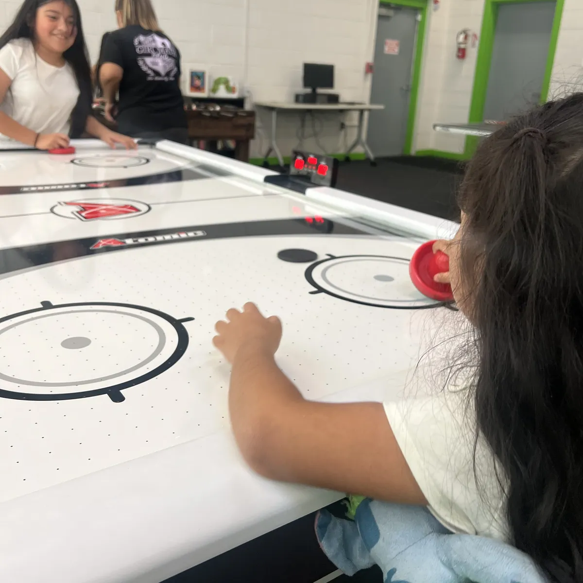 Kids playing on the repaired air hockey table